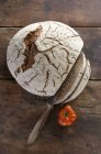 Una pagnotta di pane fresco di campagna, affettato su una superficie di legno — Foto stock