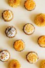 Cupcakes with vanilla cream cheese frosting decorated with sugar sprinkles and flowers on table — Stock Photo