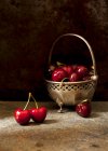 Свежие вишни в винтажной металлической чаше и на деревенской поверхности — стоковое фото