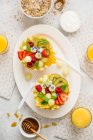A healthy breakfast: fruit salad served in melon halves, yoghurt, granola, orange juice and honey — Stock Photo