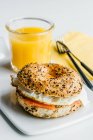 Bagel with cream cheese, salmon and egg and glass of juice drink on background — Stock Photo