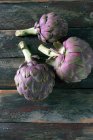 Alcachofas tunecinas púrpuras en una tabla de madera - foto de stock