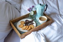A breakfast tray with biscuits and coffee in bed — Stock Photo