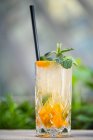 Cocktail with gin, almond syrup, lime juice, kumquats and mint in glass with straw — Stock Photo