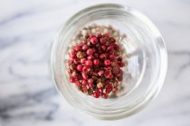 Red peppercorns in a glass on a marble surface — Stock Photo