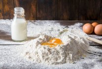 Flour milk and broken eggs on dark board — Stock Photo