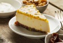 Eine Scheibe Mascarpone und griechischer Joghurt-Käsekuchen mit Dattel- und Walnussbasis, garniert mit Maracuja — Stockfoto