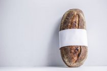 Una barra de pan de masa fermentada envuelta con un lazo blanco - foto de stock