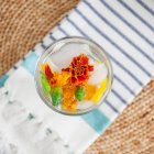 Mineral water in a glass infused with melon and edible flowers (top view) — Stock Photo