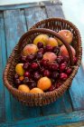 Alperces frescos, pêssegos e cerejas em uma cesta — Fotografia de Stock
