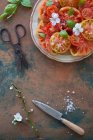 Ensalada de tomate con copos de sal marina, albahaca y flores - foto de stock