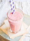 A strawberry smoothie in a glass with two drinking straws — Stock Photo