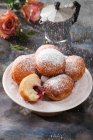 Icing sugar being sifted over a plate of jam doughnuts — Stock Photo