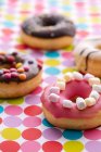 Барвисті прикрашені пончики на плямистій скатертині — стокове фото