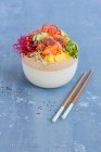 Poke bowl avec thon et saumon et baguettes sur la table — Photo de stock