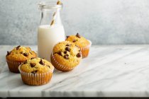 Muffin con gocce di cioccolato e una bottiglia di latte — Foto stock