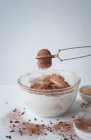 Tamizar el cacao en polvo en una mezcla de merengue de chocolate - foto de stock