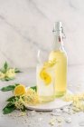 Homemade elderflower cordial in a glass with fresh lemon and ice — Stock Photo