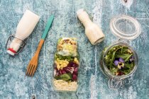 Quinoa and orzo pasta salads in glass jars, with dressing and a wooden fork — Foto stock