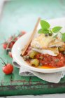 Filetti di pesce su pomodori con olive verdi — Foto stock
