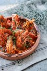 Gambas with garlic and tomato sauce and herbs in a rustic serving dish — Stock Photo