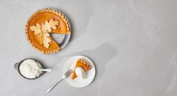 Pumpkin pie, cut and served with cream — Stock Photo