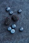 Blackberries and blueberries on a stone background — Stock Photo