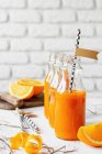 Jugo de naranja con vitamina fresca en botellas en el mostrador de cocina - foto de stock
