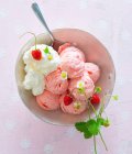 Un tazón de helado de fresa, crema batida y fresas silvestres - foto de stock