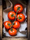Fresh red tomatoes in a rustic wooden container — Stock Photo