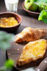 Croissants com engarrafamento de pêssego em tábua de madeira e em tigela — Fotografia de Stock
