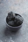 Three black truffles in a grey bowl — Stock Photo