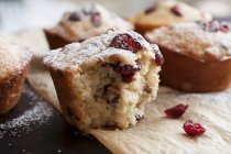 Freshly baked cranberry muffins on parchment paper with sugar icing — Stock Photo