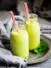 Зеленые веганские коктейли в стеклянных бутылках с соломинками — стоковое фото