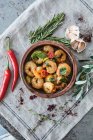 Garlic prawns with tomatoes and fresh herbs in rustic serving dish - foto de stock
