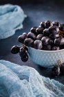 Blue ceramic bowl of red grapes and cloth on table — Stock Photo