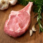 One raw Veal Chop with herbs and garlic on cutting board — Stock Photo