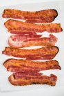 Fried slices of bacon on kitchen roll (seen from above) — Stock Photo