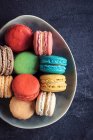 Sweet and colorful macaroon cookies in the plate on dark background — Stock Photo