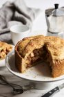 Apple pie, partly sliced on cake stand — Stock Photo