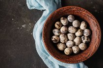 Quail eggs in clay bowl with blue cheesecloth — Stock Photo