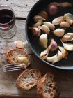 Pan-fried cloves of garlic with baguette bread — Stock Photo