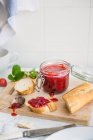 Strawberry jam in a glass jar, and spread on a slice of white bread — Stock Photo
