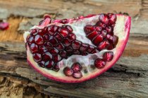 A piece of pomegranate on a wooden surface — Stock Photo