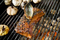 Pork and garlic cloves on a grill — Stock Photo