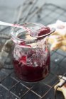 Currant jam in a jar with a spoon for filling jam biscuits — Stock Photo