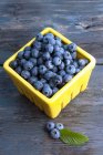 Fresh blueberries in the wicker basket on wooden table, selective focus — Stock Photo