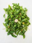 Basilikum-Pesto in Arbeit - Basilikumblätter mit Mandeln, Knoblauch, Salz und Parmesan vor grauem Hintergrund — Stockfoto