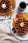 Waffles with berries, butter and maple syrup served with coffee (seen from above) — Stock Photo