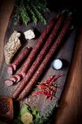 Longues saucisses de porc avec des rouleaux de lin et des piments séchés sur une planche à découper en bois — Photo de stock